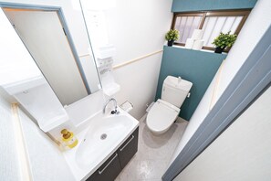 Ein kleines Badezimmer mit einem weißen Waschbecken, einer Toilette und einem Fenster mit Blick.