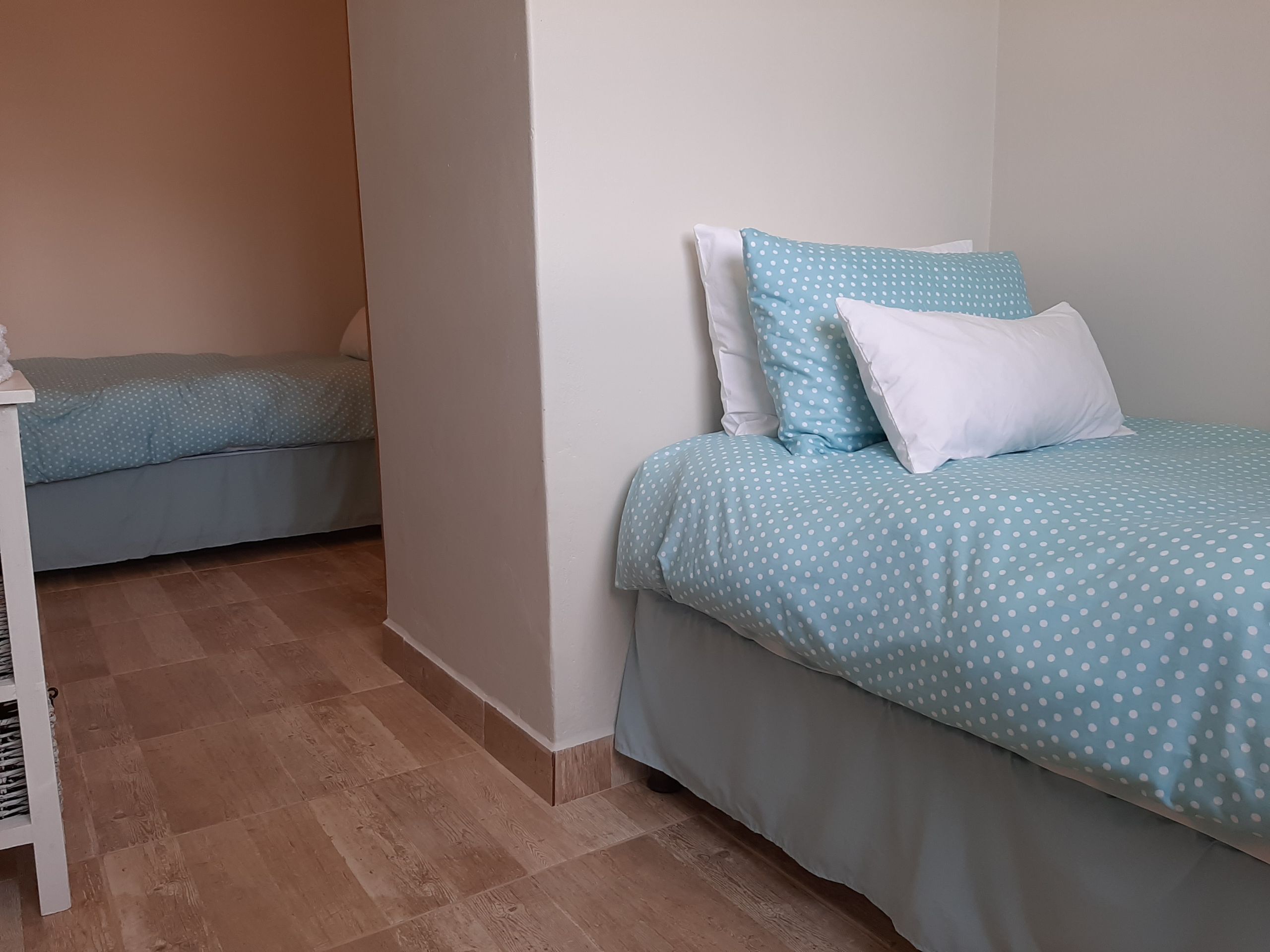 Une chambre avec deux lits, chacun recouvert d’une couvre-lit à pois bleus et agrémenté d’oreillers blancs.