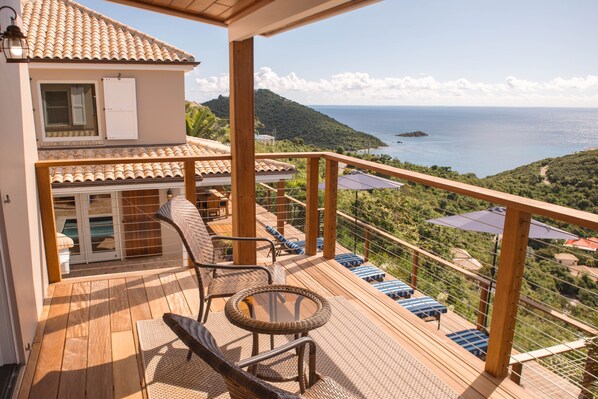 A wooden deck with wicker furniture and a view of the sea. - Villa Zusammen- Gorgeous Views Above Klein Bay! South shore View (St John)