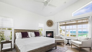 A bedroom with a large bed, a fireplace, a sofa, and a view of the ocean. - Island Cottage Inn - Adults Only (Flagler Beach)