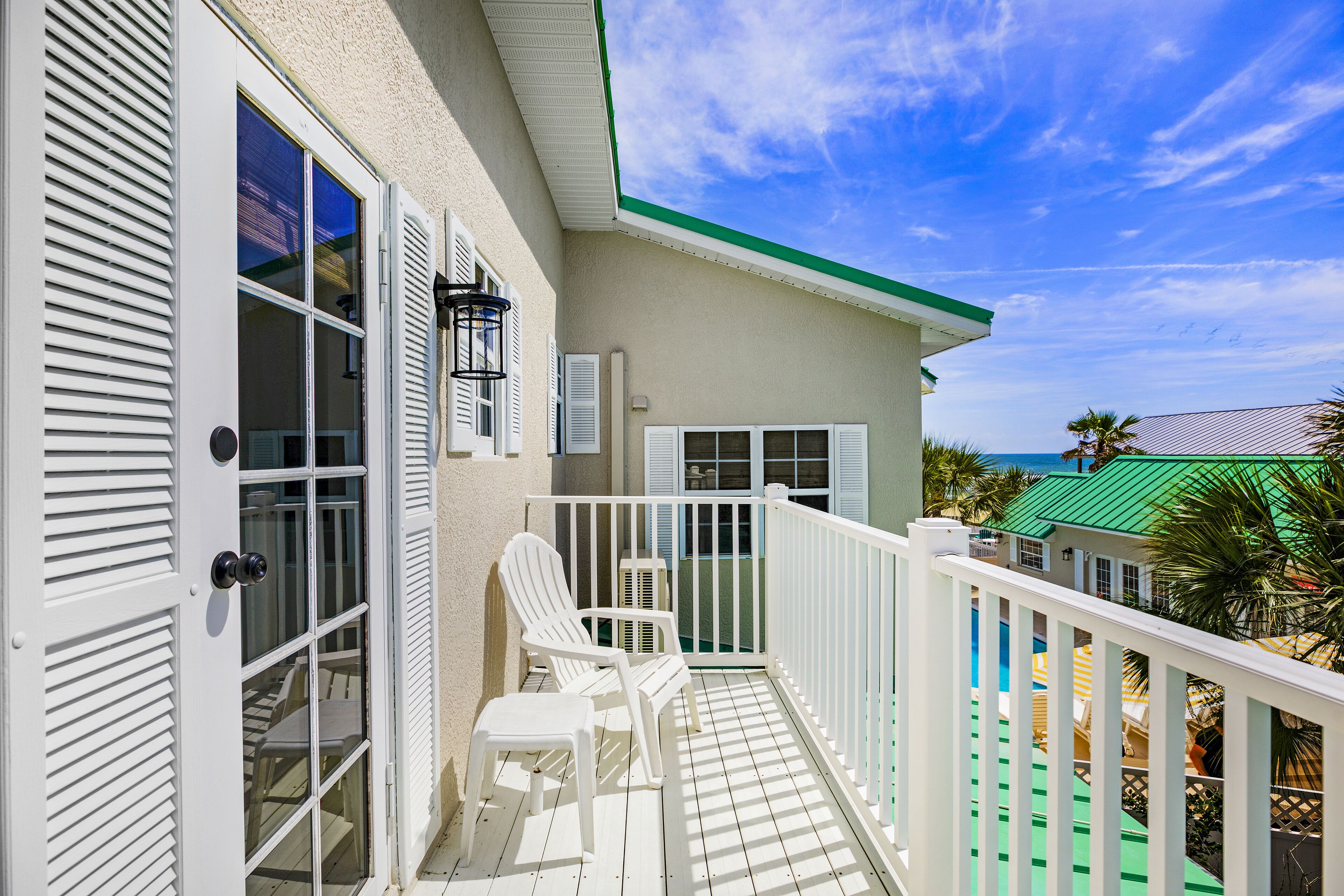 A balcony with white railings, a white chair, and a small table.