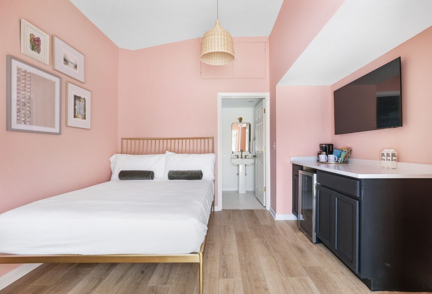 A bedroom with a bed, a bedside table, a TV, and a bathroom visible through an open door.