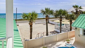 A pool area with a view of the beach, palm trees, and a clear sky. - Island Cottage Inn - Adults Only (Flagler Beach)