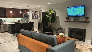 A modern living room with a grey sofa, a coffee table, and a TV mounted on the wall. - Lovely Shaw Apartment - Sleeps 4, WALK to White House (Washington)