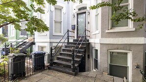 A residential building with a front entrance, a staircase leading to the second floor, and a small garden area with plants and mulch. - Lovely Shaw Apartment - Sleeps 4, WALK to White House (Washington)