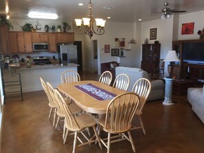 Una cocina amplia con armarios de madera, una isla central y un comedor con mesa y sillas de madera.