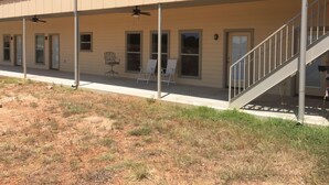 A two-story building with a covered patio area, a staircase, and a row of windows. - Willow Knoll 2 Texas (Fredericksburg)
