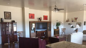 A spacious living room with a large TV, wooden cabinets, a purple sofa, and a ceiling fan. - Willow Knoll 2 Texas (Fredericksburg)