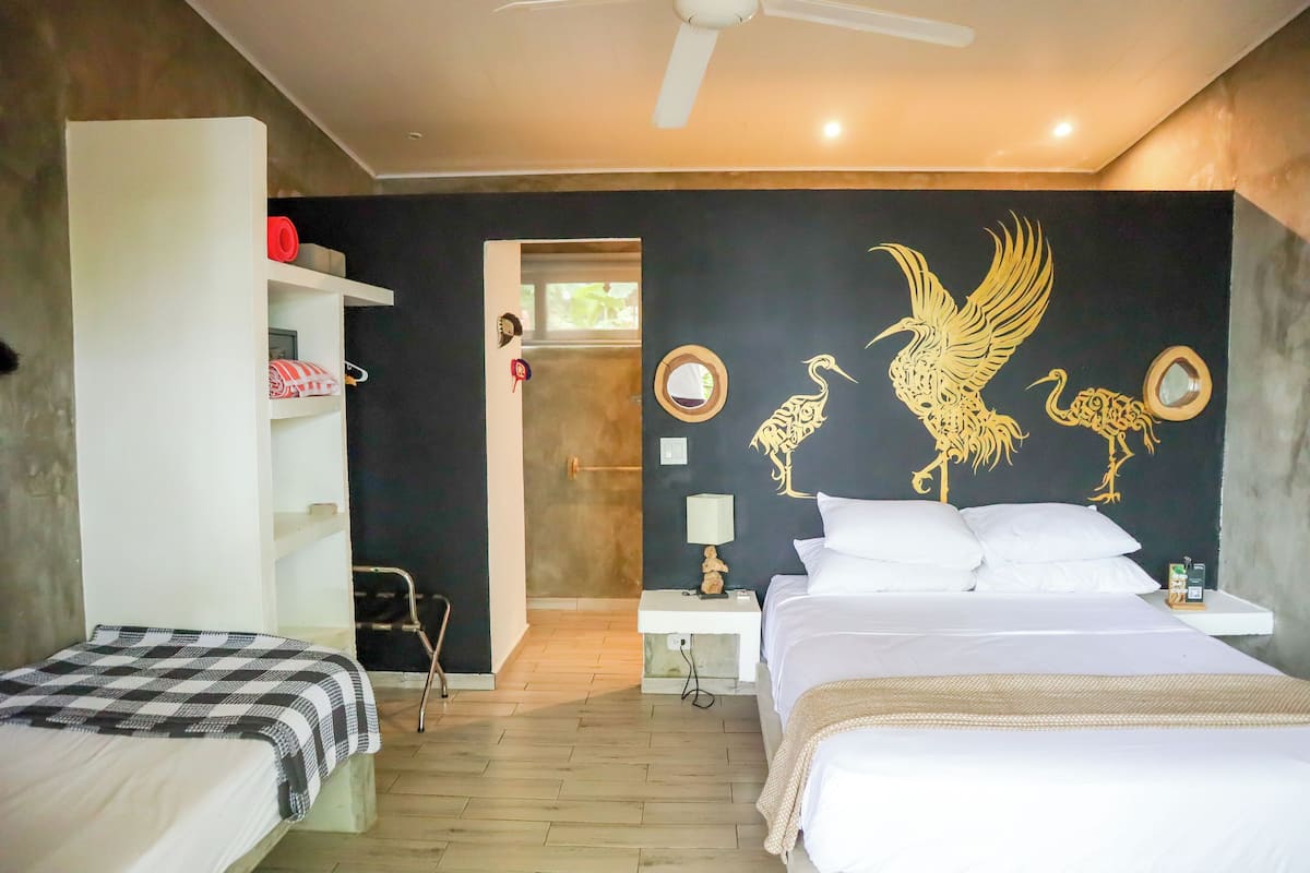 Une chambre d’hôtel comprenant un lit, une table de chevet avec une lampe, une armoire et un mur orné d’un motif décoratif.