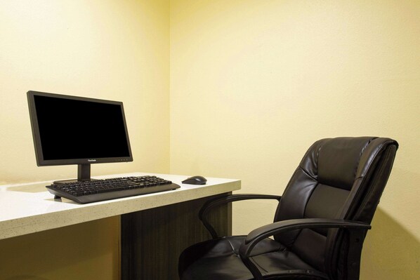 A computer desk with a monitor, keyboard, and mouse, and a black leather chair.