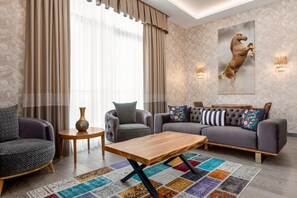 Una sala de estar moderna con un sofá, sillones, una mesita de centro y una alfombra.
