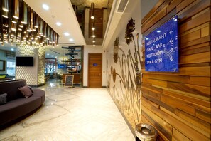 Un vestíbulo moderno con una pared de madera, un letrero direccional azul y un piso de mármol.