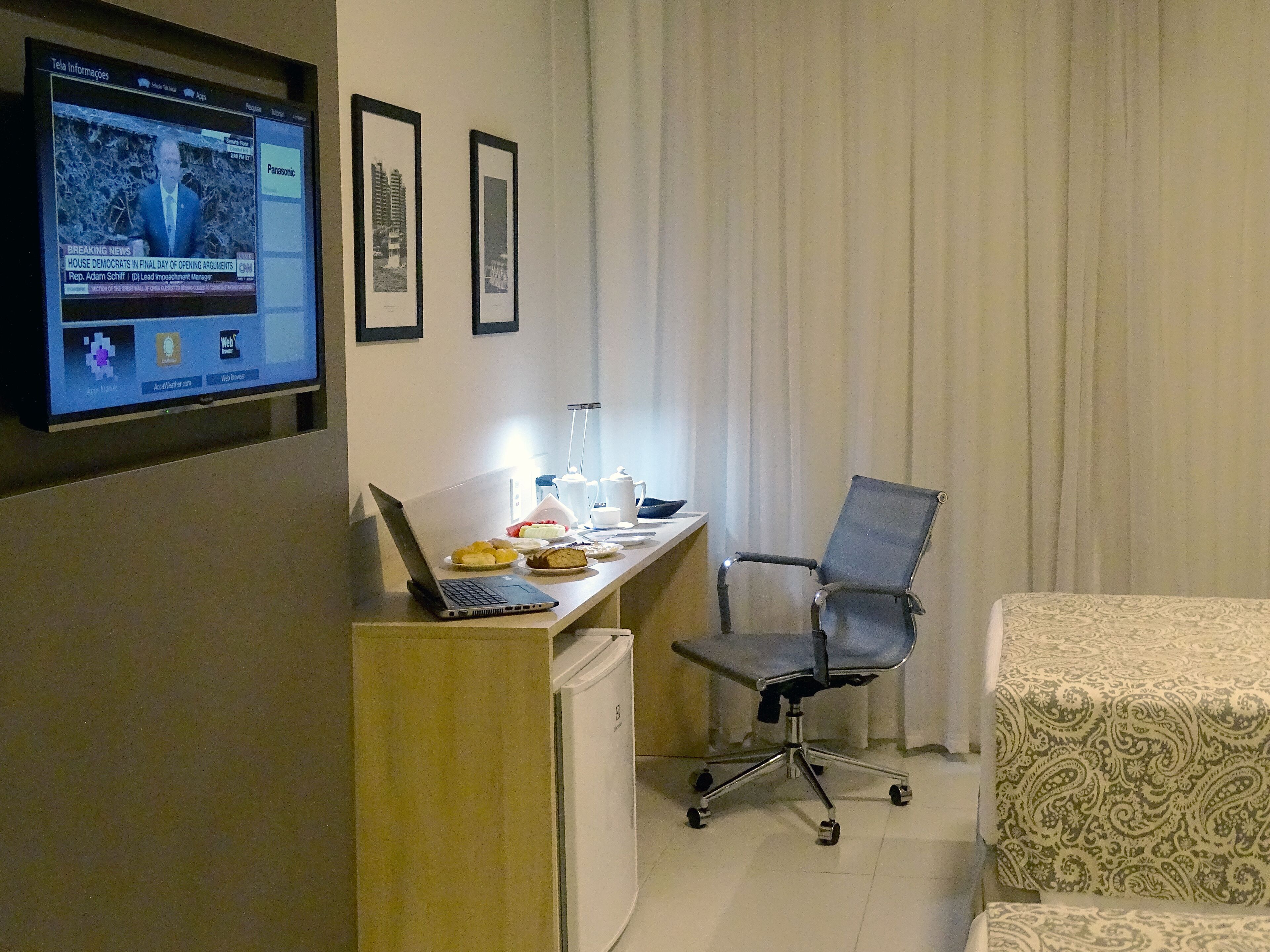 A hotel room with a desk, laptop, chair, and bed.