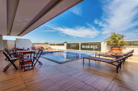 Una piscina al aire libre, sillones reclinables de piscina