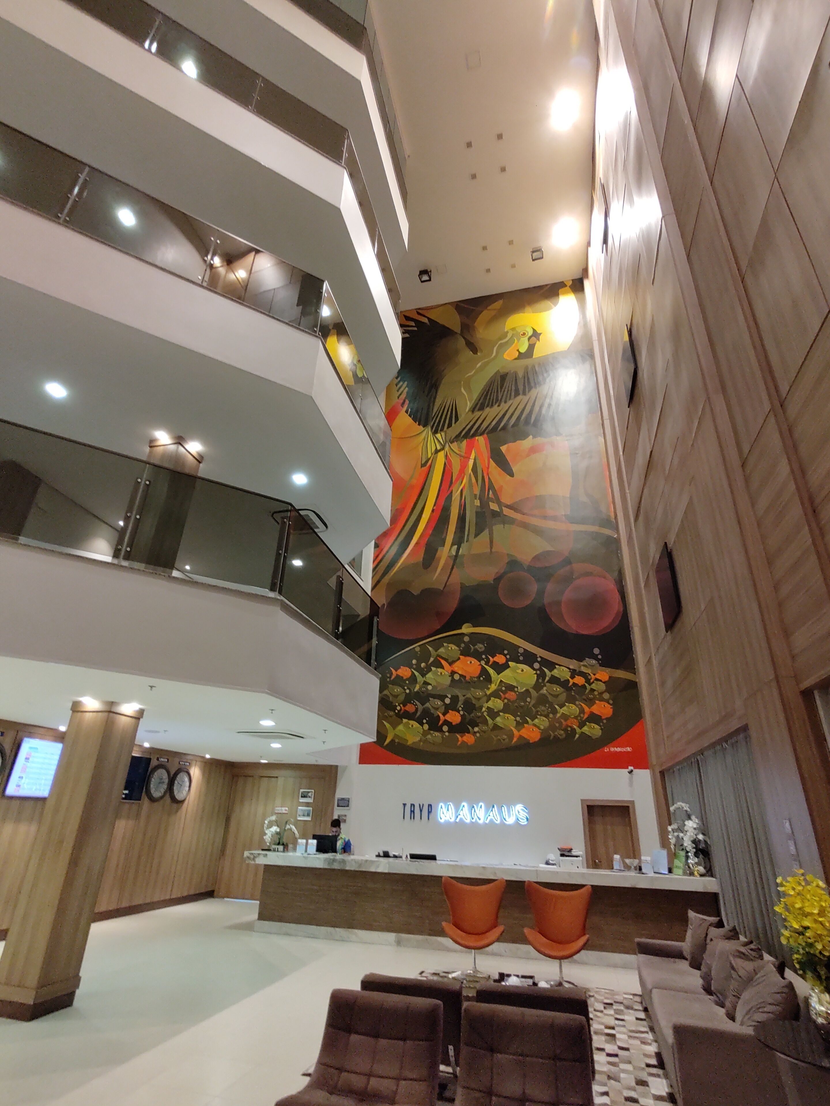 A multi-level hotel lobby with a large mural, a reception desk, and seating areas.
