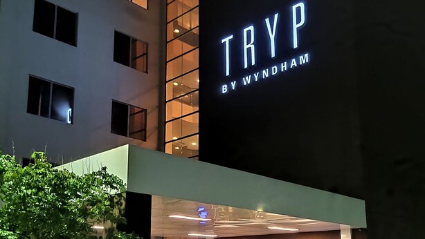 Un edificio moderno con un llamativo letrero iluminado que dice "TRYP BY WYNDHAM".