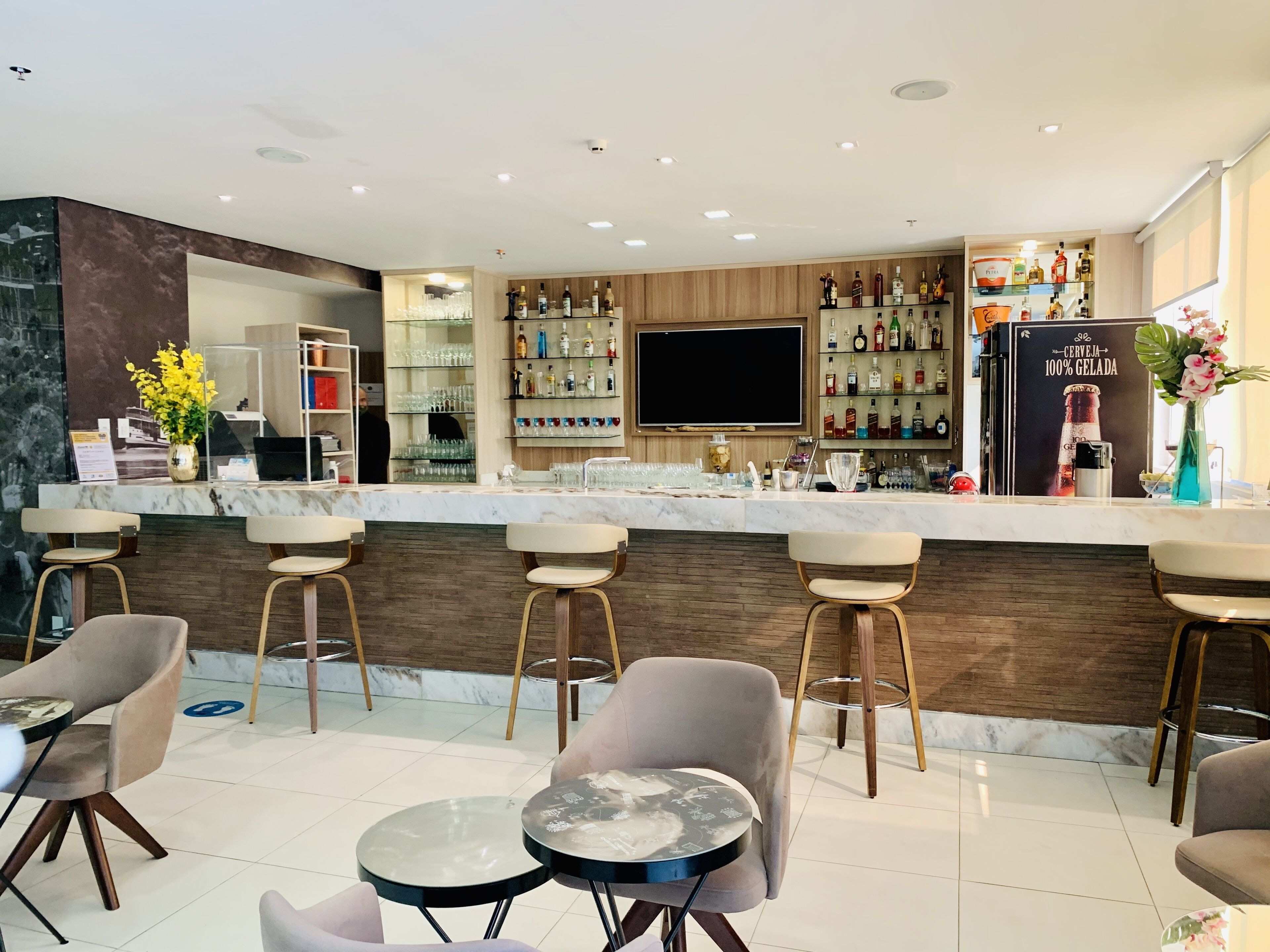 Een moderne bar met een marmeren aanrecht, barstoelen en diverse drankflessen.