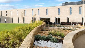 A modern building with a flat roof, rectangular windows, and a landscaped garden with various plants and rocks. - Ramada by Wyndham Leeds East (Leeds)