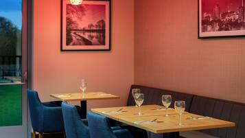 Un restaurant avec deux tables, des chaises bleues et un banc.