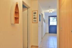 Passadís amb una porta de fusta, una porta blava i una petita finestra amb cortines.