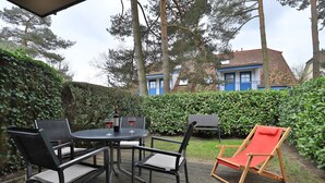 An outdoor patio with a round table, four chairs, and a red lounge chair. - Papillon Whg. 12/4, Germany (Ostseebad Boltenhagen)