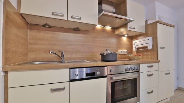 A modern kitchen with wooden cabinetry, stainless steel appliances, and a built-in oven. - Papillon Whg. 12/4, Germany (Ostseebad Boltenhagen)