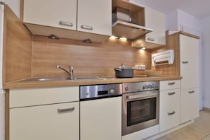 A modern kitchen with wooden cabinetry, stainless steel appliances, and a built-in oven.