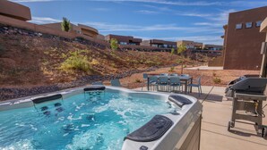 A hot tub with a view of a hillside and modern buildings in the background. - Cliffside Retreat (St. George)