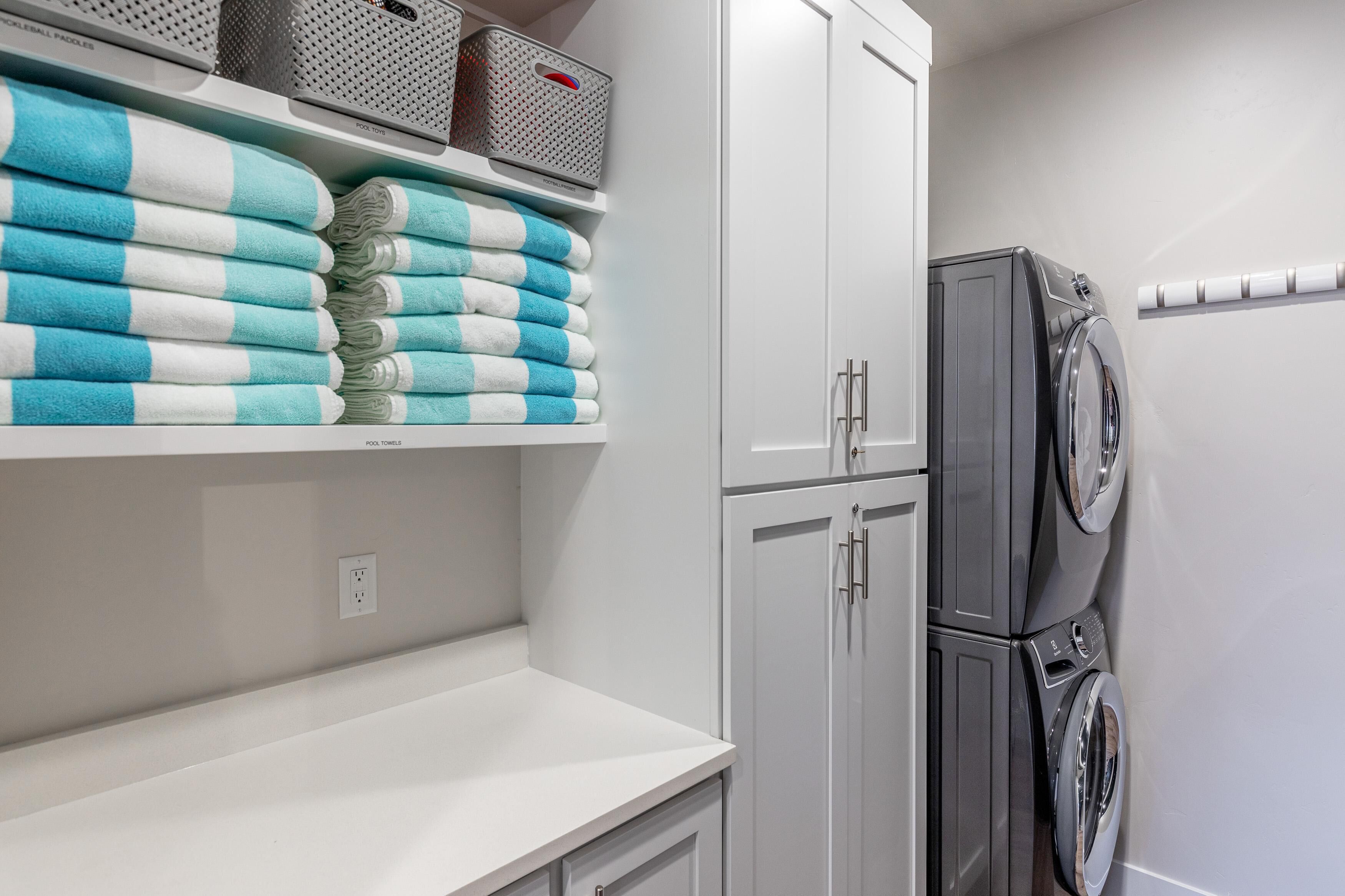 A laundry area with stacked towels, a washing machine, and storage baskets.