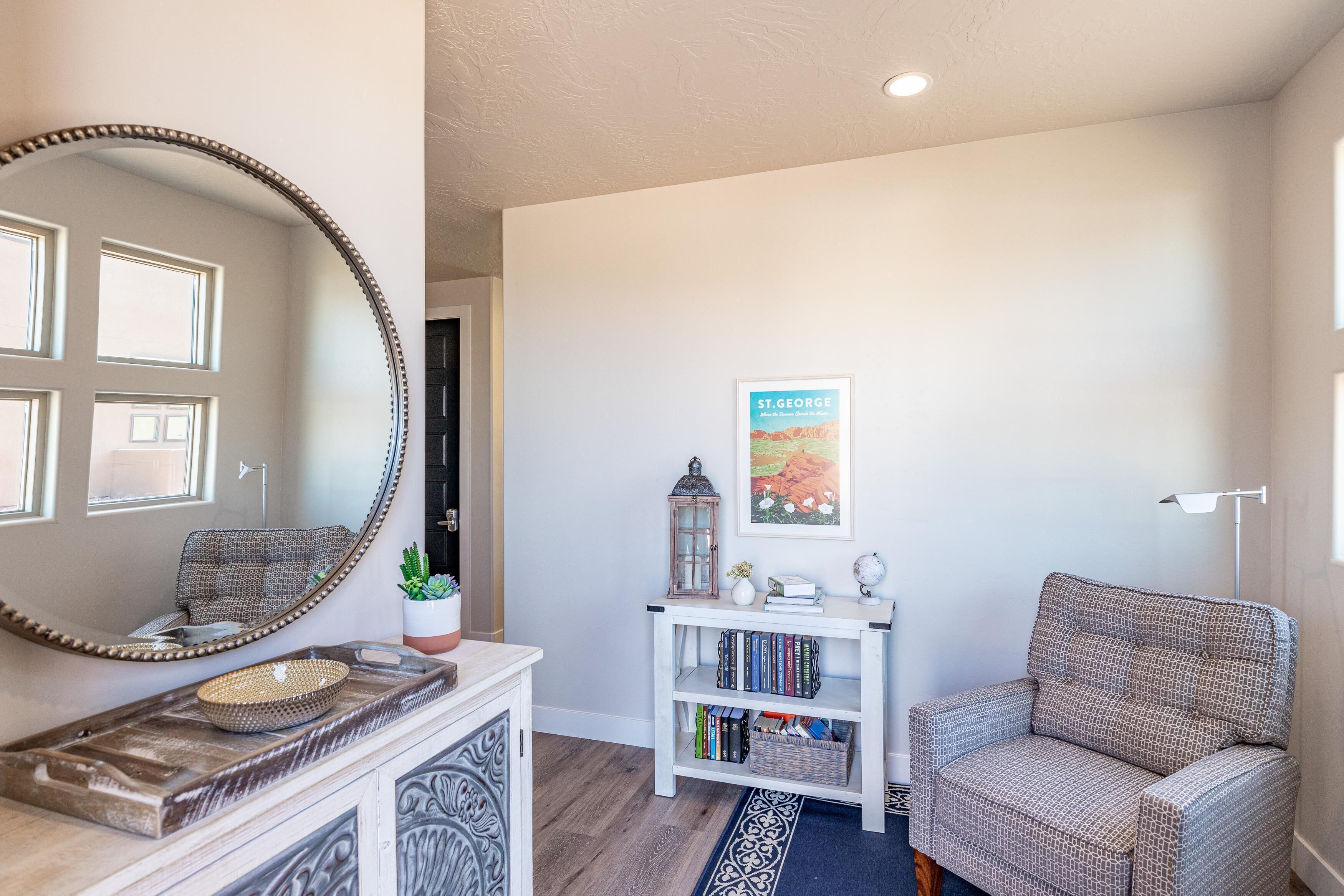 A room with a large mirror, a bookshelf, a chair, and a framed picture on the wall.