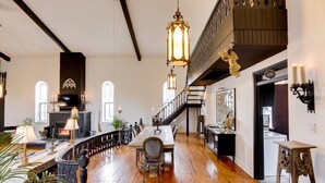 A spacious dining area with a long wooden table, a staircase, and a bar area with a sign.