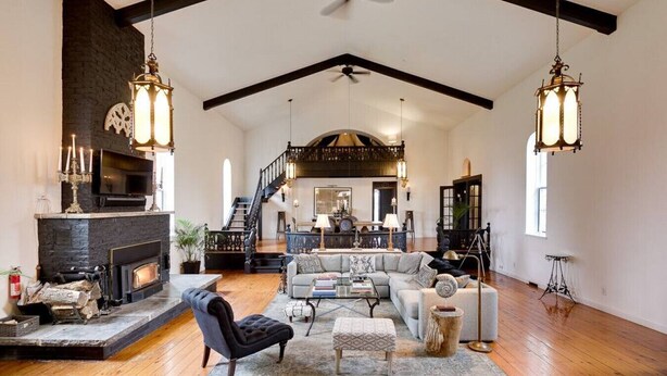 A spacious living room with a fireplace, a staircase, and a large sofa.