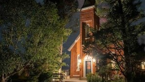 A brick church with a bell tower, surrounded by trees and a starry night sky.