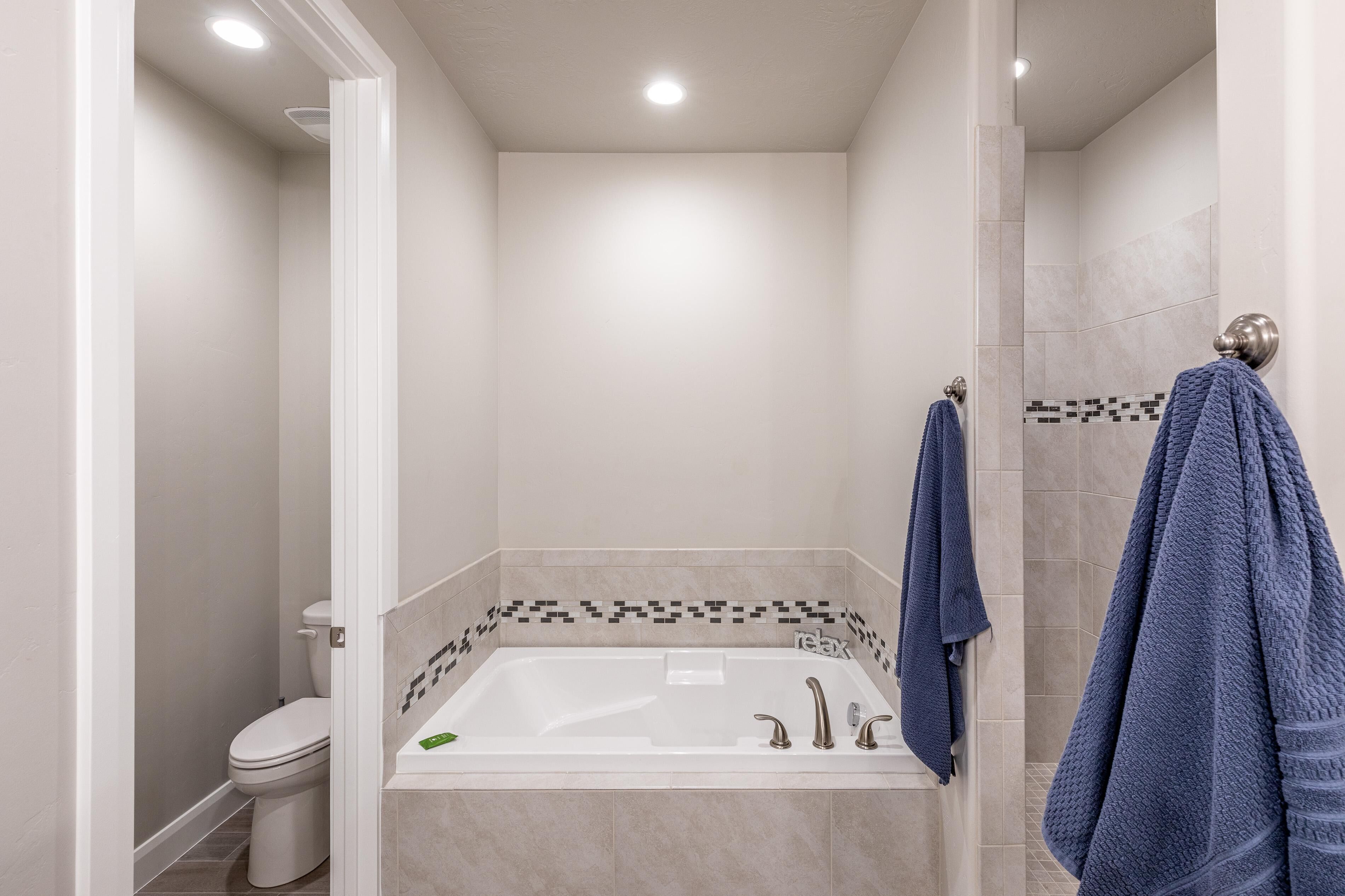A modern bathroom with a bathtub, toilet, and shower area.