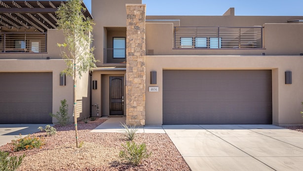 A modern two-story house with a stone pillar, a garage, and a small garden area. - Poolside Paradise (St. George)