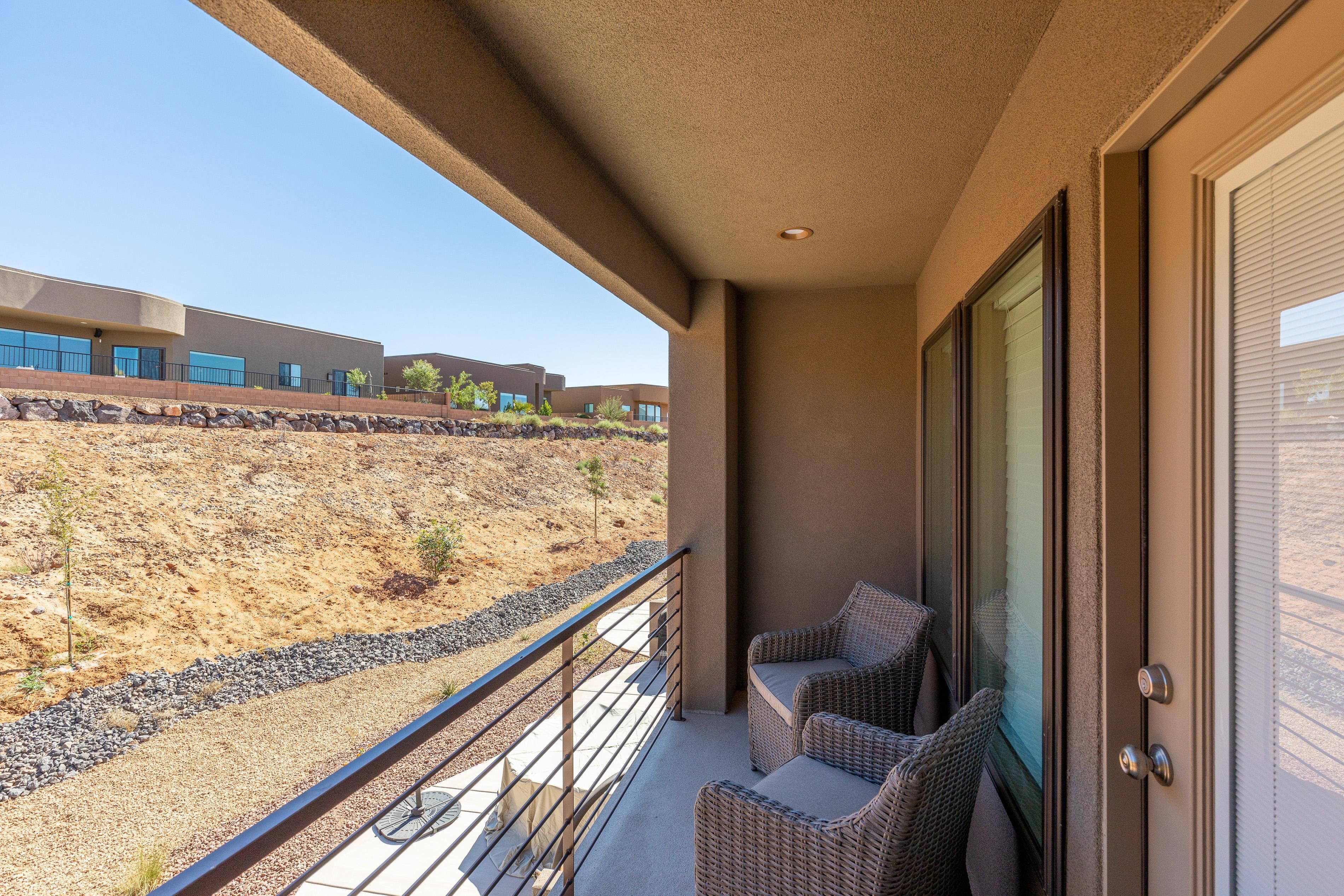 A balcony with wicker furniture, a view of a building, and a rocky landscape.