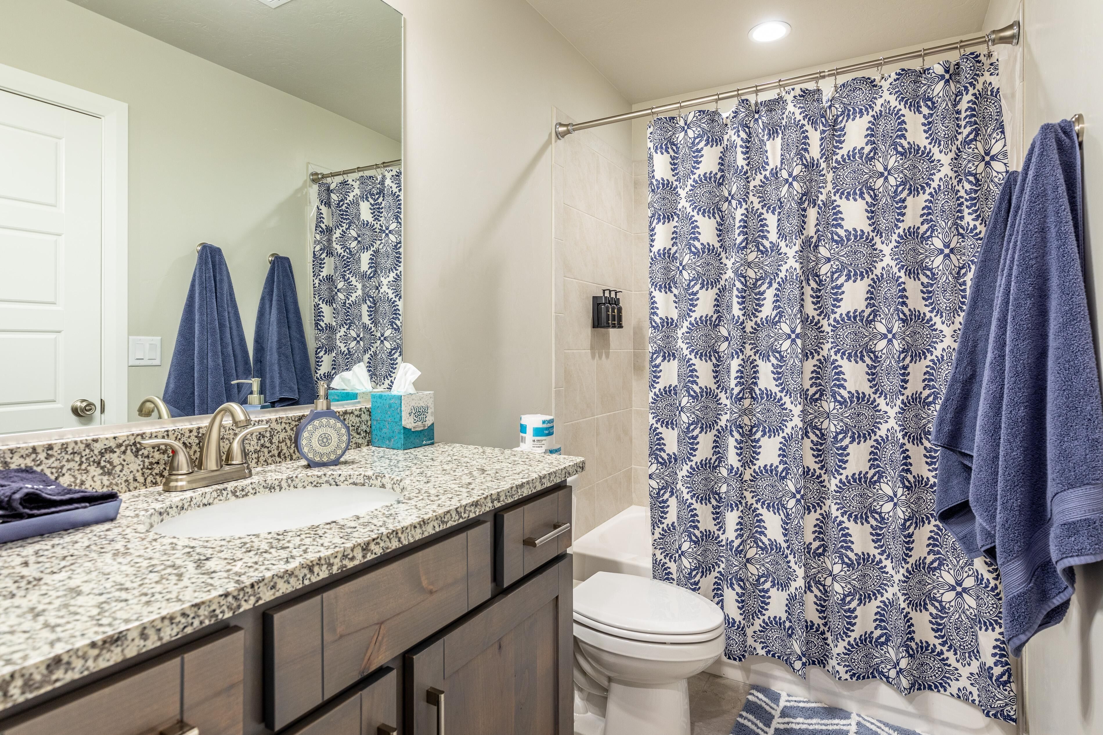 Un baño con lavamanos doble, inodoro y cortina de ducha con estampado floral.