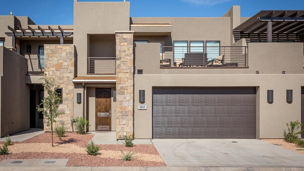 A modern two-story house with a stone facade, a large garage, and a covered patio. - Launchpad (St. George)