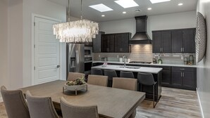 Una cocina moderna con armarios oscuros, una isla central y una lámpara de araña.