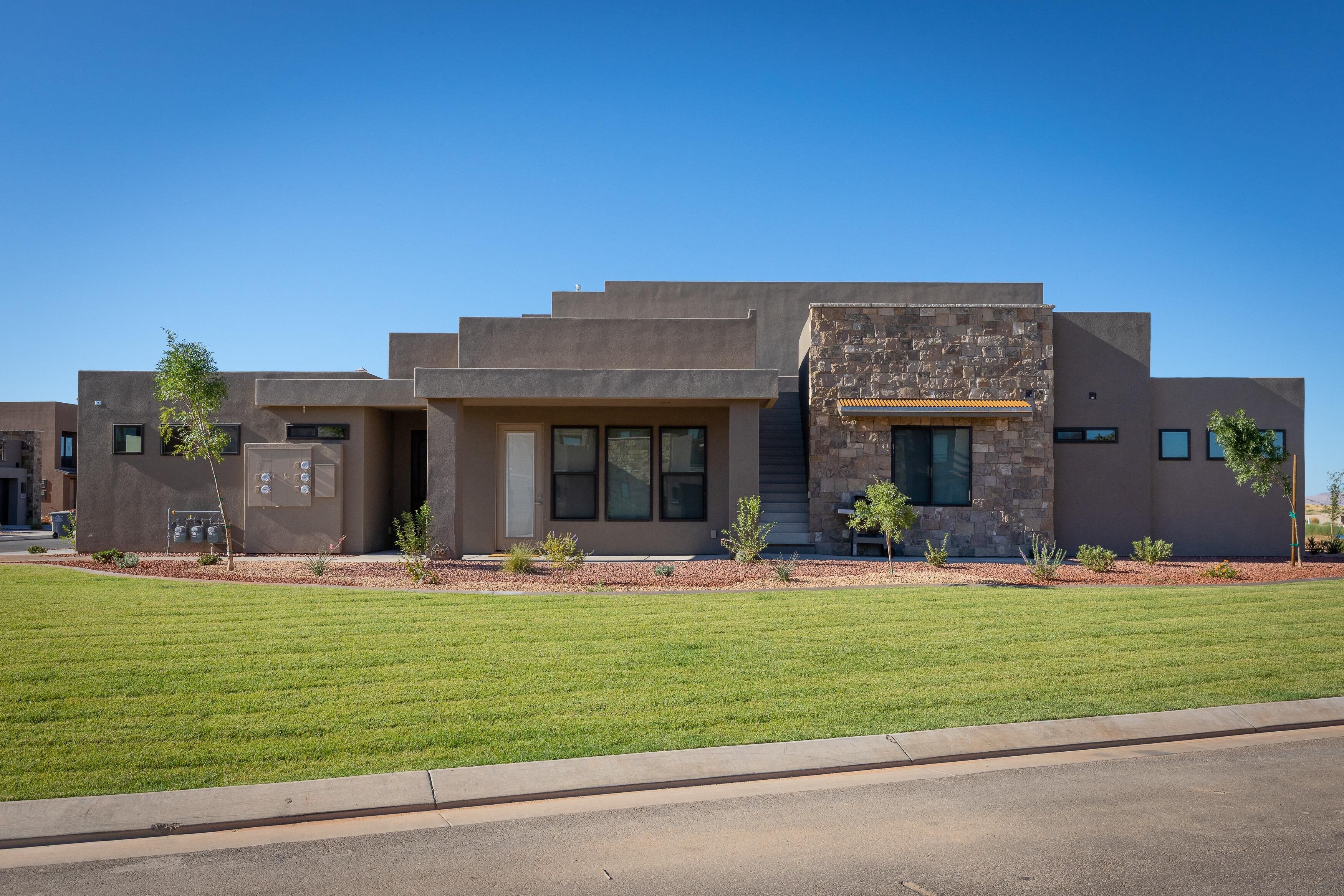 A modern two-story house with a flat roof, large windows, and a stone accent wall.
