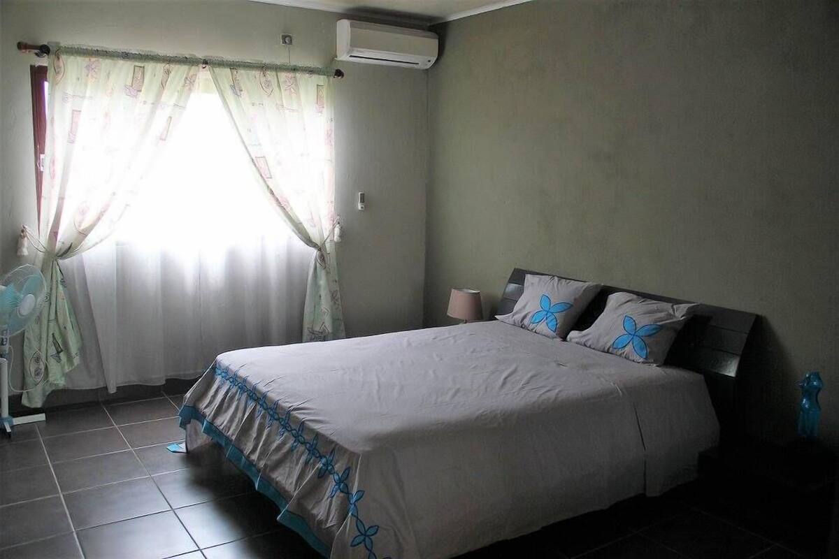Een slaapkamer met een bed, gordijnen, een airconditioner en een bedlamp.