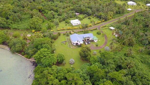 An aerial view of a large property with multiple buildings, surrounded by dense tropical vegetation and a coastline. - Lausikula Chambres d'hôtes (Wallis Island)