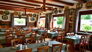 En restaurant med flere borde og stole, træbjælker og forskelligt vægpynt.
