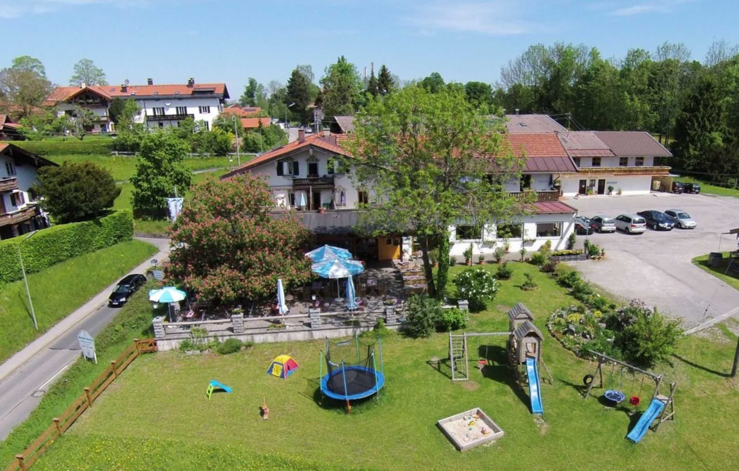 A residential area with a playground, a trampoline, and a small building with a slide.