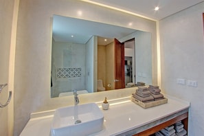 A modern bathroom with a large mirror, a white sink, and a towel rack with neatly folded towels.