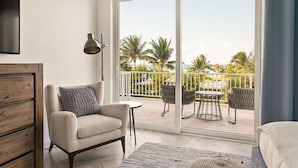 A modern living room with a sofa, a small table, and a balcony with outdoor furniture. - Ocean Terraces Two Bedroom 2 (Nassau)