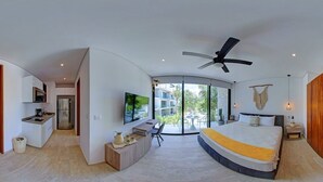 A modern bedroom with a bed, a desk, and a TV. There is a balcony with a view of the outside. - Trendy Studio, PANORAMIC D 202 – By Salt-Kisses (Tulum)
