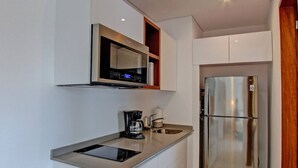 A modern kitchen with a stainless steel refrigerator, a built-in microwave, and a coffee maker. - Trendy Studio, PANORAMIC D 202 – By Salt-Kisses (Tulum)
