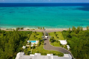 Vista aérea de un resort con piscina, exuberante vegetación y una playa.