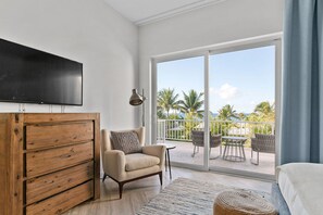 Una habitación moderna con un aparador de madera, un televisor de pantalla plana, un sofá y un balcón con mobiliario exterior.